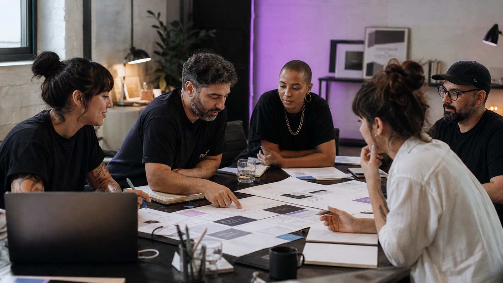Equipe reunida em escritório planejando ações de marketing com materiais impressos sobre a mesa